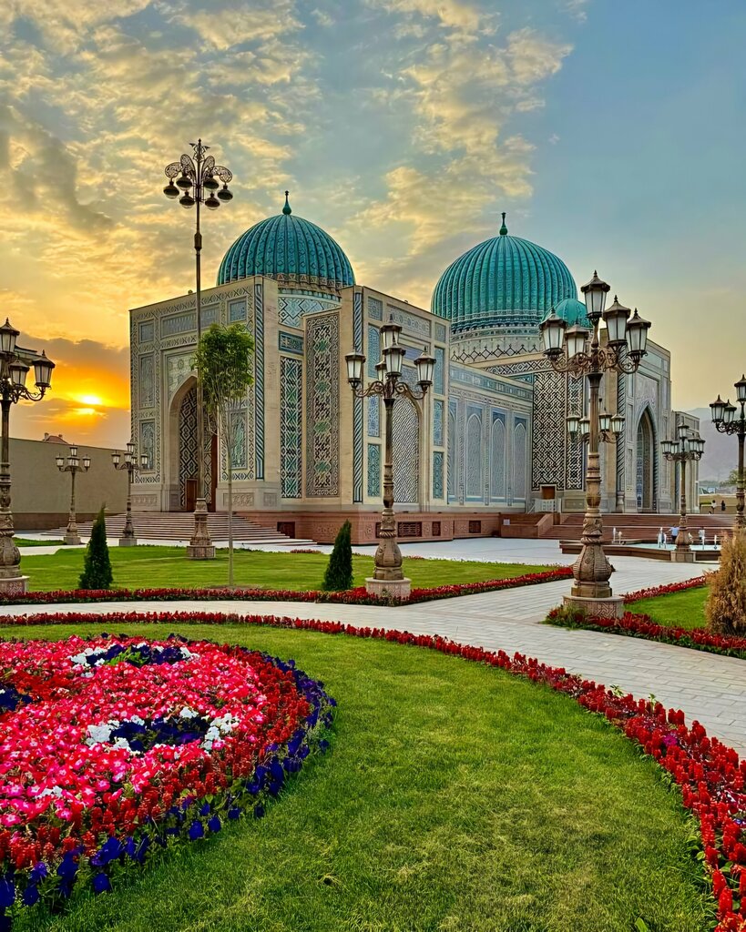 Turquoise-domed architecture and flower gardens in Khujand at sunset